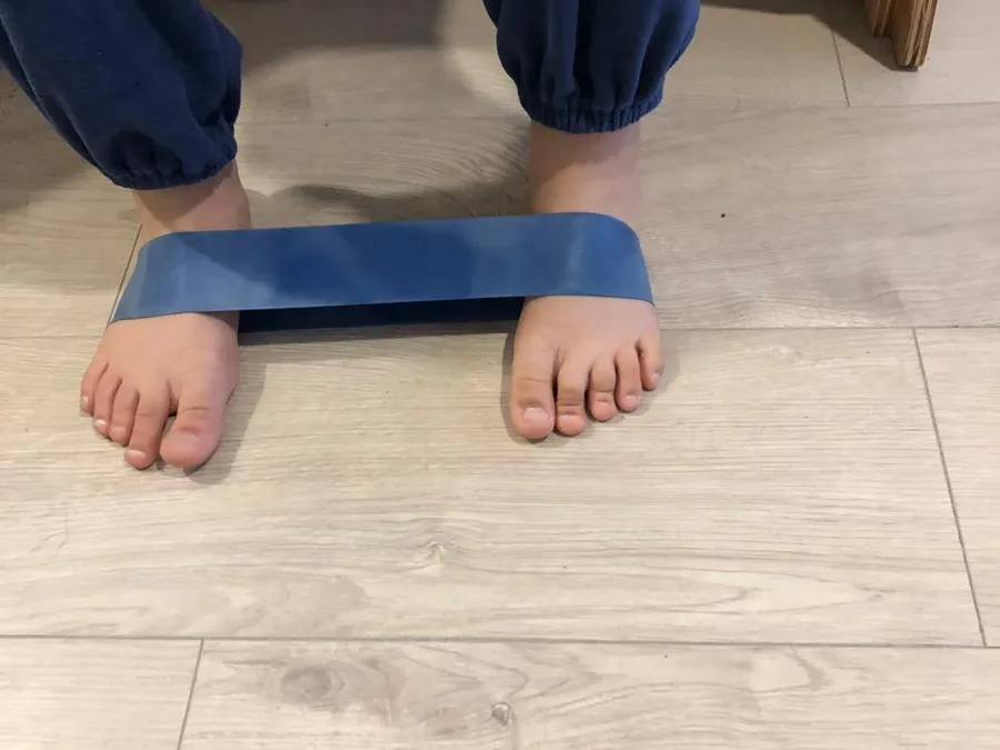 Ejercicio de pies con banda elástica en kinesiología traumatológica infantil